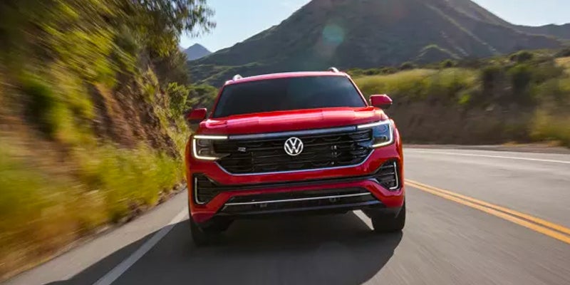 A red Volkswagen Atlas shot head-on as it drives down the highway