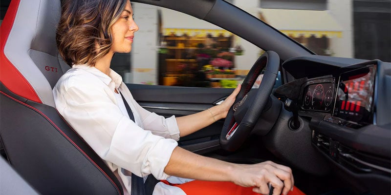 A woman behind the wheel of a luxurious, comfortable, and refined Volkswagen Golf GTI