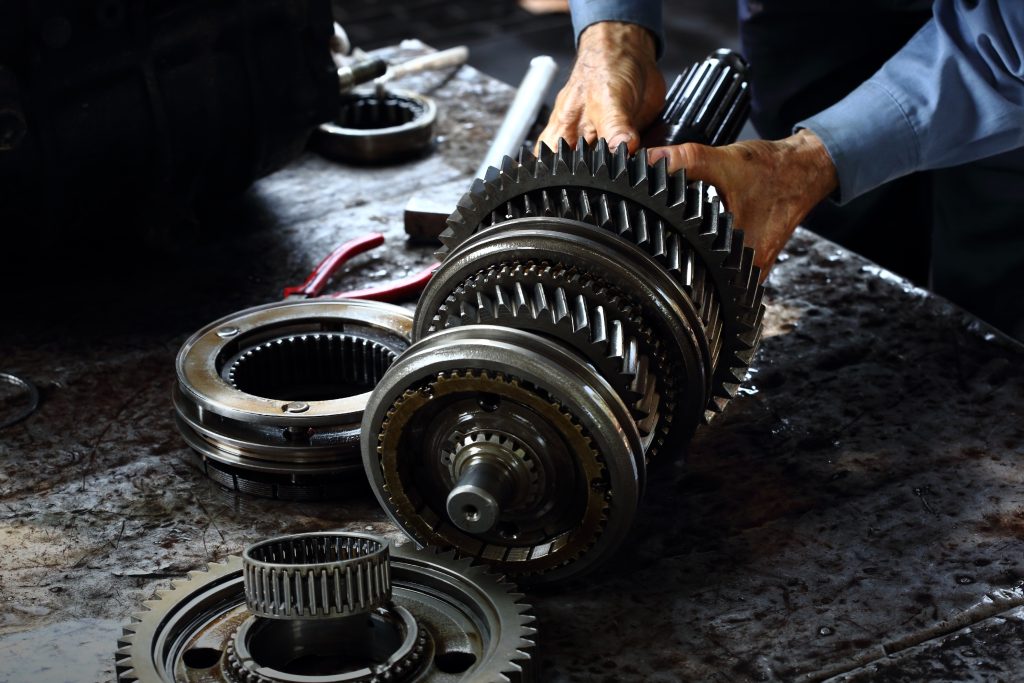 A mechanic holding a partially disassembled transmission.