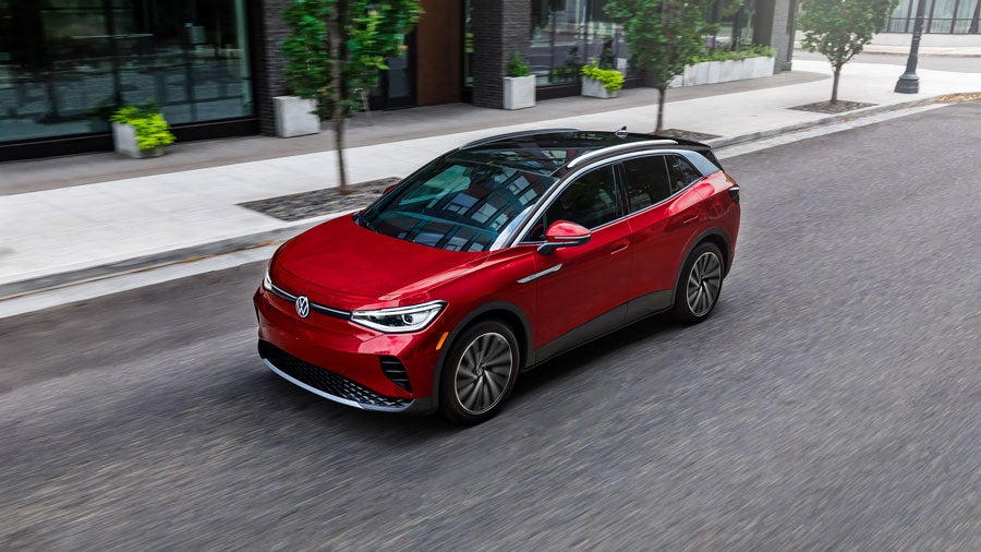 Front, medium-angled shot of an ID.4 SUV shown in Aurora Red Metallic, driving on a city street.